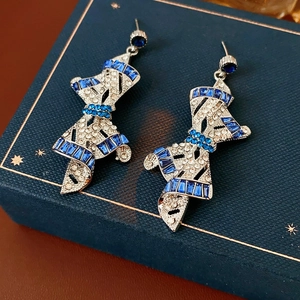 Detail of silver bow earrings with blue crystals on a navy star patterned gift box