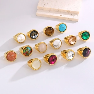 Golden stainless steel rings with colorful gemstones and crystals in minimalist display