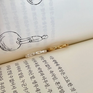 Detailed close-up of gold and silver chain textured rings placed within a book spine