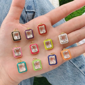 Colorful rectangular enamel pendants with gold frames and clear crystals in hand