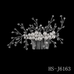 Detailed shot of bridal hair comb with white pearls and sparkling crystal flowers
