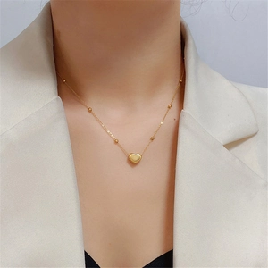 Titanium steel gold heart pendant necklace with beads on model wearing beige suit