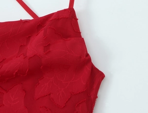 Gros plan sur le tissu jacquard rouge avec motifs de feuilles et franges sur la robe