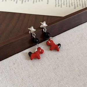 Detail of star and red horse drop earrings featuring polished beads and silver accents