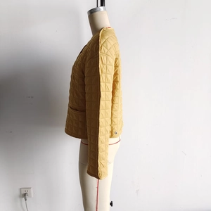Detail view of yellow quilted jacket with square stitching on a professional mannequin