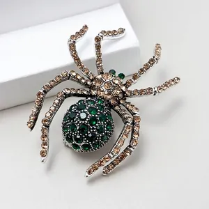 Macro view of spider brooch featuring green crystals and champagne rhinestones