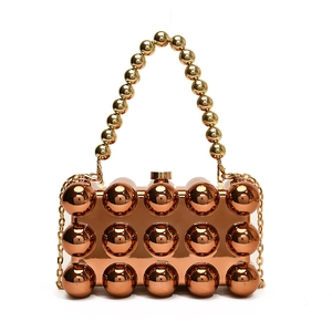Detailed close-up of rose gold acrylic clutch with metallic sphere rivets and bead handle