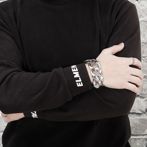 Close-up of polished stainless steel chunky Cuban link bracelet and ring on male model