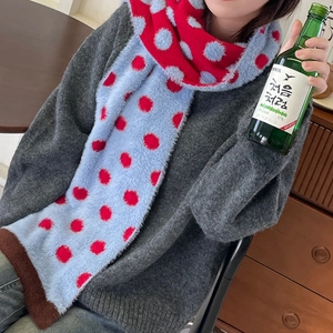 Detail of blue and red polka dot faux mink scarf with brown trim on a cozy model