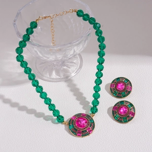 Détails d'un collier et boucles d'oreilles géométriques aux cristaux verts et roses