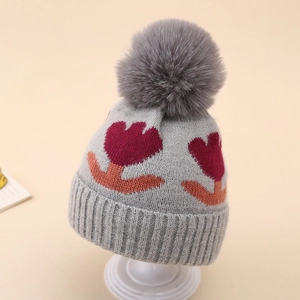 Detailed knit texture of grey baby beanie with flower patterns and soft pompom