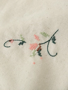 Détails de broderie florale au point de croix sur tissu en coton et lin blanc cassé