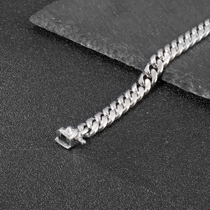 Macro shot of polished silver Cuban link chain with box clasp on dark textured background