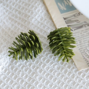 Artificial green pine cones for Christmas decoration on rustic newspaper and white fabric