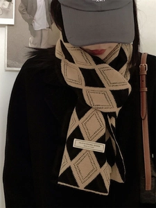 Détail d'une écharpe tricotée d'hiver avec des motifs losanges noir et beige et étiquette