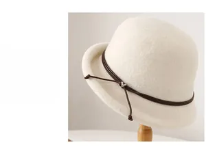 Detail of wool cloche hat with brown leather cord and silver heart buckle on wooden stand