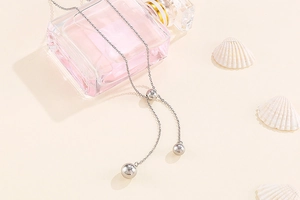 Detail view of a silver Y-shaped stainless steel necklace with polished bead pendants