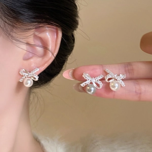Elegant 18k gold plated bow stud earrings with pearl pendant shown on a model's ear