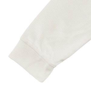 Macro shot of white waffle knit fabric texture and cuff detail on a men's Henley shirt
