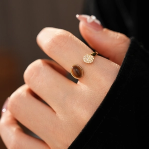 Détail macro d'une bague ouverte dorée avec pierre oeil de tigre et zircons brillants
