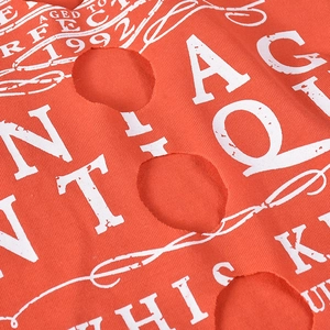 Detailansicht von orangefarbenem Strickstoff mit Vintage-Druck und Distressed-Ausschnitten
