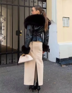 Détail d'une veste en cuir noire à col fourrure et d'une jupe longue beige fendue chic