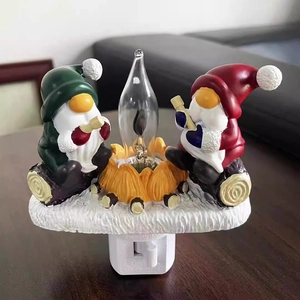 Close-up of resin Christmas gnomes sitting by a campfire with clear light bulb and white plug