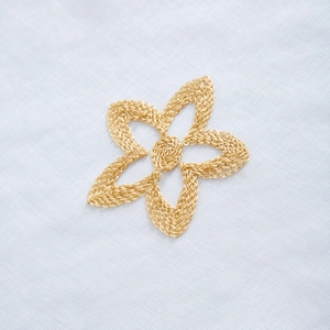 Detailed close-up of golden floral embroidery on a light blue kitchen cafe curtain fabric