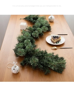 Detailed view of dense pine needle garland on a wooden table for festive dining decor