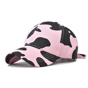 Detail of pink and black cow print cotton baseball cap with curved brim and soft texture