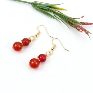 Detail view of handmade gold wire wrapped earrings with red agate crystal beads