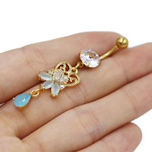 Detailed view of a golden navel ring with blue marquise crystals held in hand