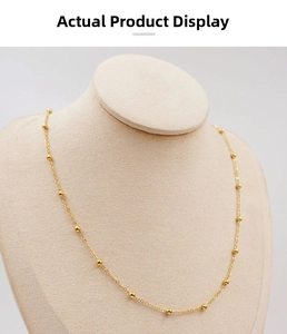 Detail of a gold titanium steel bead chain necklace displayed on a beige jewelry bust