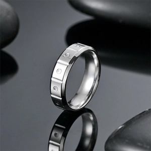 Close-up of a silver titanium steel ring with geometric patterns on a black stone base