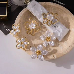 Macro view of assorted floral pearl earrings in golden stainless steel on marble