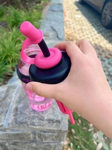 Detail of a large pink and black sports water bottle with straw and brand lettering