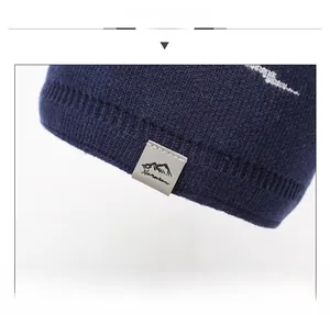 Close-up of navy blue ribbed knit beanie featuring a grey leather logo patch with mountain