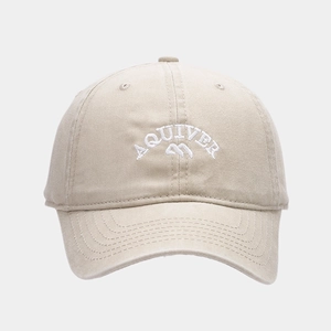 Detailed close-up of white 3D embroidery on washed beige cotton baseball cap
