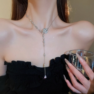 Close-up of sparkling diamond camellia necklace with elegant silver water drop tassels