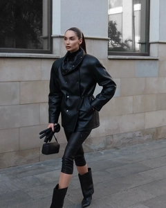 Détail d'une veste en similicuir noir avec col montant et cordon de serrage à la taille