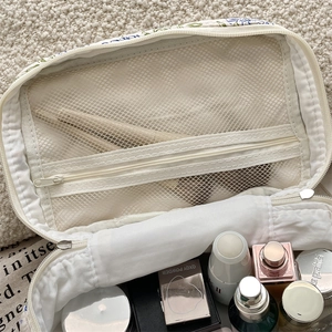 Detail showing blue floral quilted makeup bag interior with mesh pocket and zipper