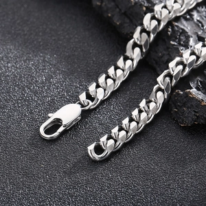 Macro shot of silver Cuban link chain with lobster clasp on dark textured background