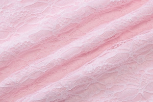 Detail shot of delicate pink floral lace fabric with intricate mesh texture and soft folds