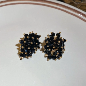 Macro detail of cluster stud earrings with black crystals and gold metal beads