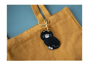 Détail du porte-carte chat noir en cuir attaché à la bandoulière d'un sac jaune