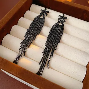 Boucles d'oreilles pendantes noires avec fleurs en zircon sur une boîte à bijoux en velours