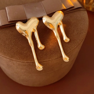 Close-up of golden heart-shaped tassel earrings on brown velvet gift box texture