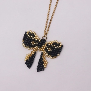 Handmade MIYUKI bead bow necklace with black and gold patterns on a fine gold chain