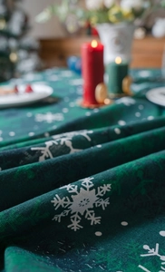 Gros plan d'une nappe de Noël vert foncé avec motif flocon blanc et texture de tissu tissé