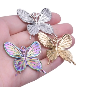 Butterfly charms for necklaces in gold, silver, and rainbow steel on a hand palm